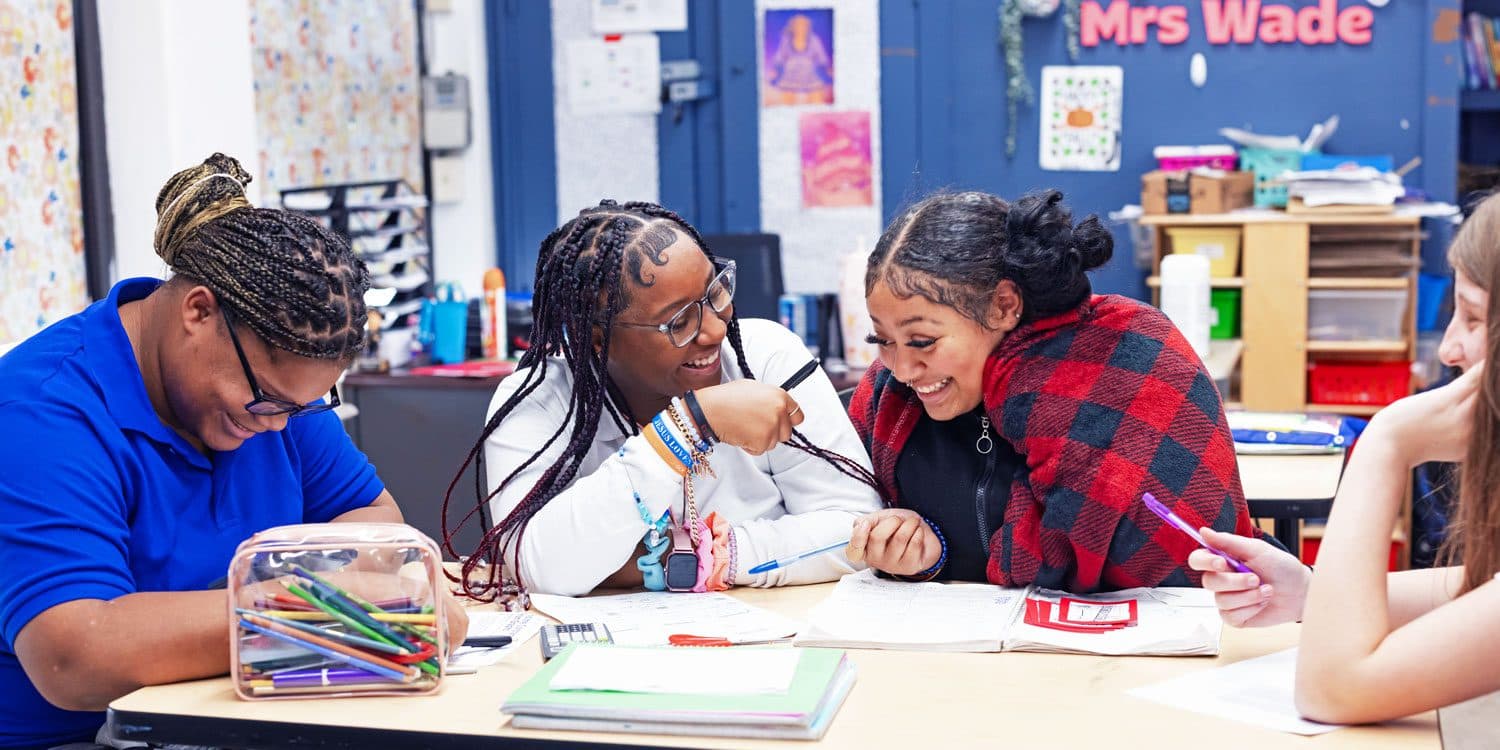 Smiling students working together at a classroom table.
